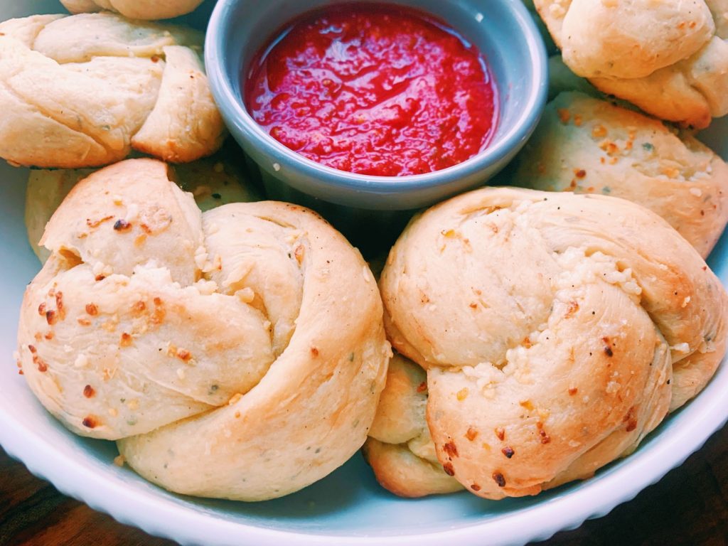 Garlic knots on a plate with marinara sauce. 