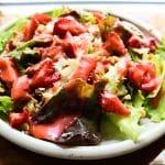 lettuce, strawberries, cheese on white plate with strawberry dressing