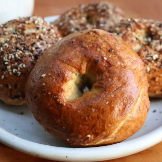 four bagels on a white plate with a wood background