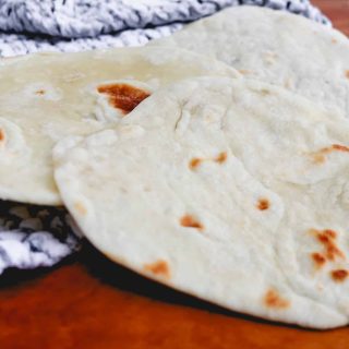 white flour tortillas on top of a black and white tea towel on a counter
