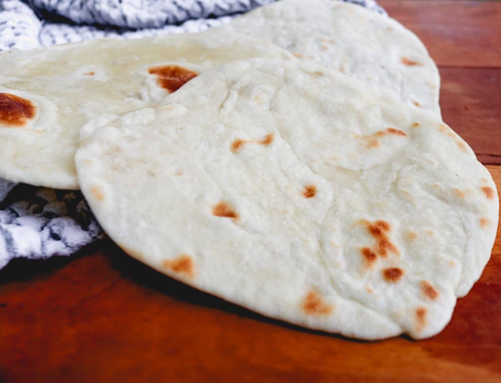 white flour tortillas on a counter with a blue and white stripe towel