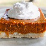 pumpkin pie bar slice on a white plate with whipped cream on top
