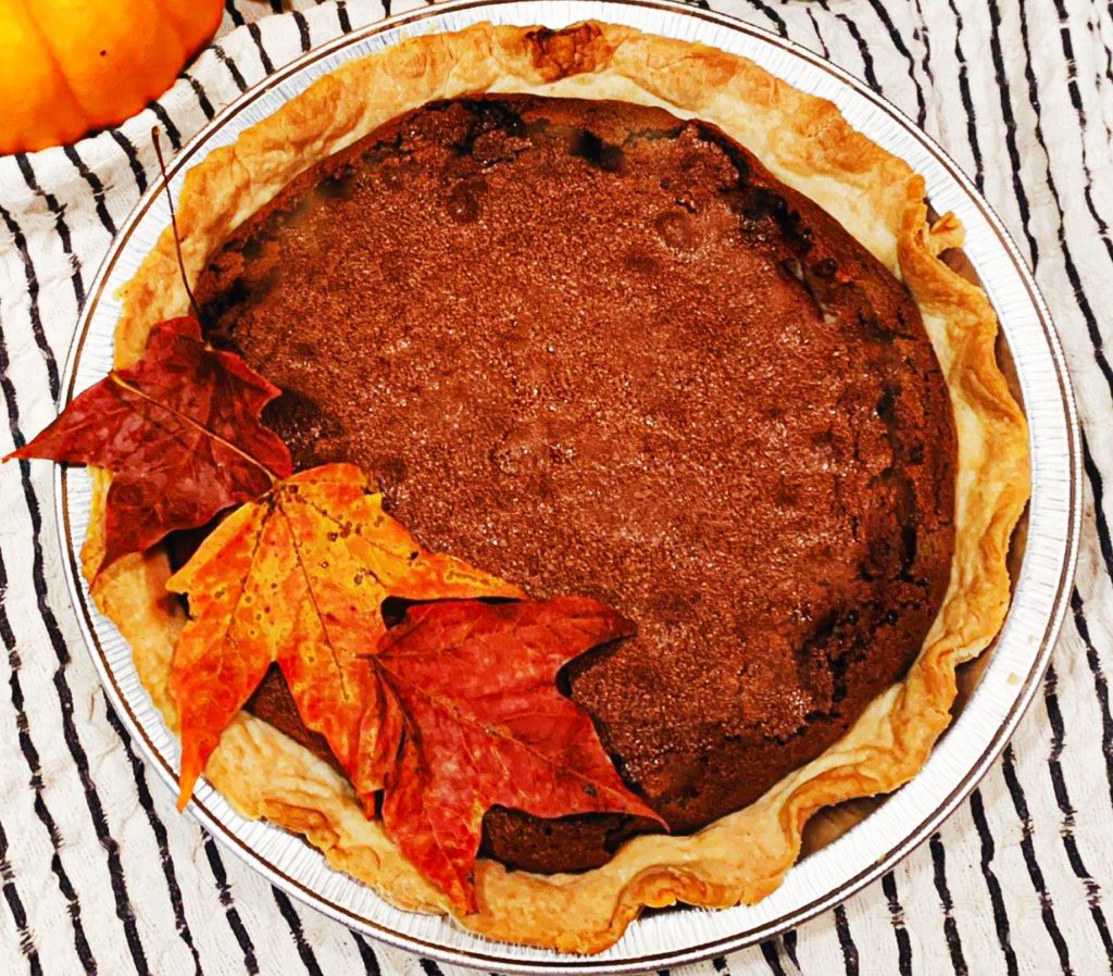 chocolate pie on a black and white tea towel with leaves scattered on top