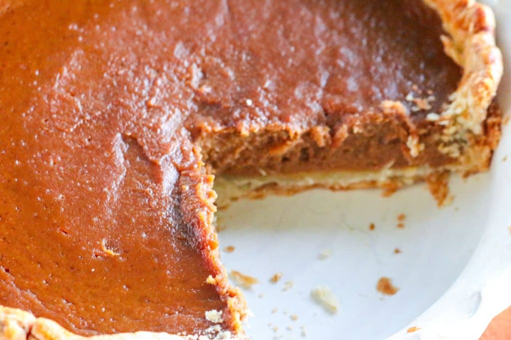 apple butter pumpkin pie with one slice missing in a white pie dish