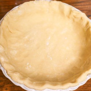 unbaked sourdough pie crust in a white pie plate