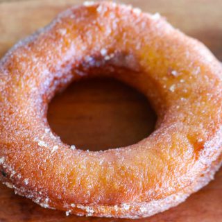 pumpkin donut with glaze on a wooden counter